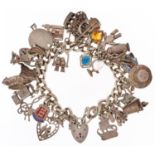 Silver charm bracelet with a large collection of mostly silver charms and love heart padlock,