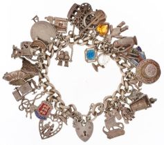 Silver charm bracelet with a large collection of mostly silver charms and love heart padlock,
