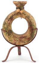 Medieval style partially red painted terracotta flask raised on metal three footed stand, 30.5cm