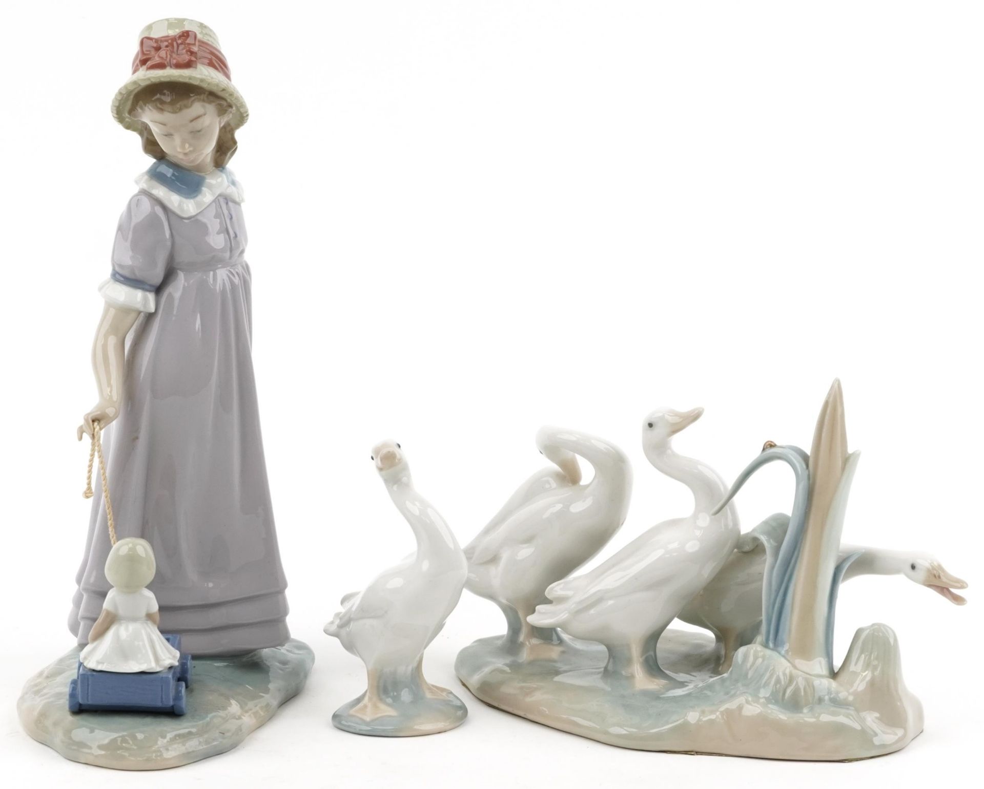 Lladro model of a girl with her doll in a cart together with a model of geese and a single goose,