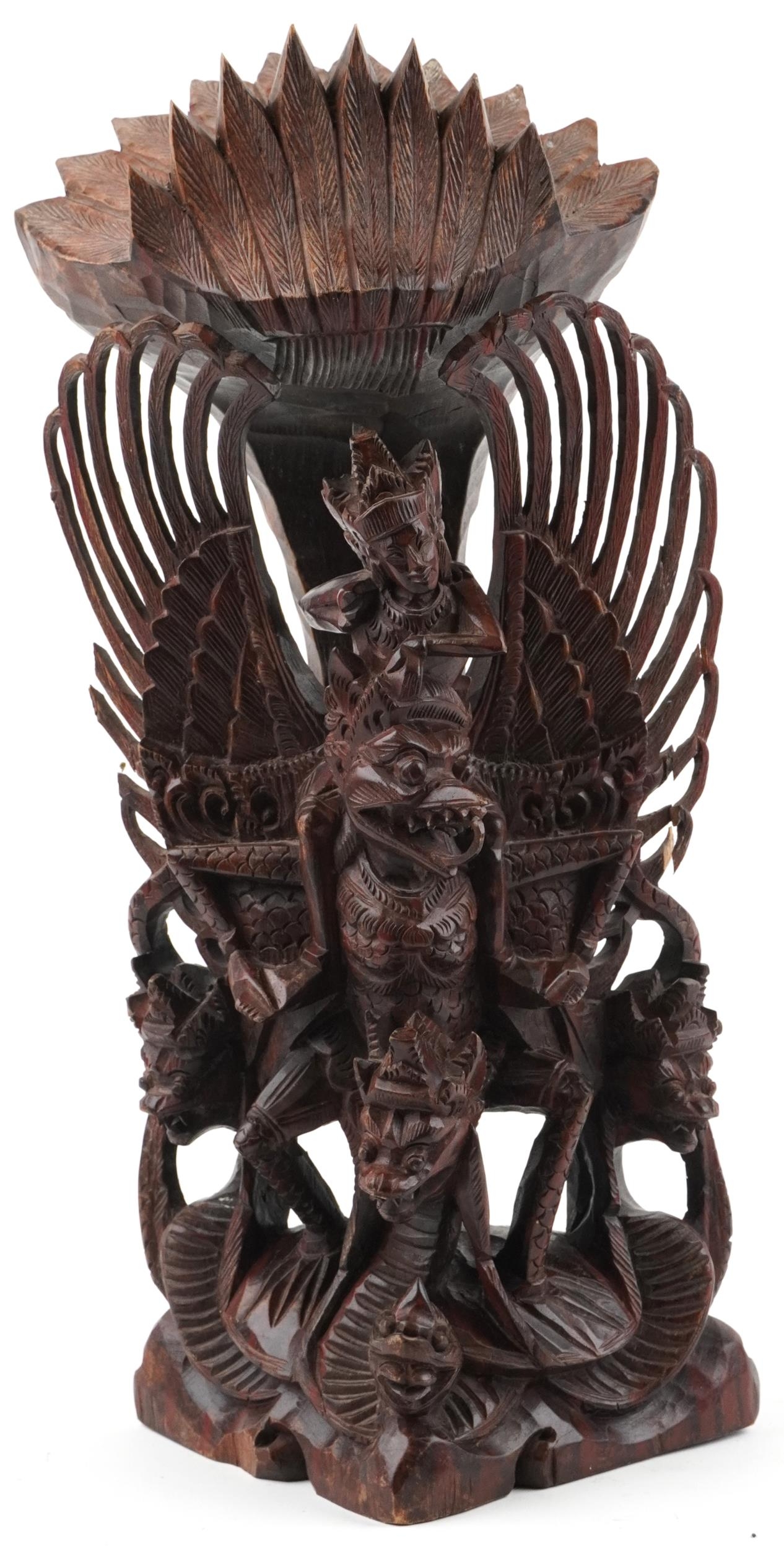 Large Burmese hardwood carving of a deity and mythical animals, 56cm high