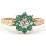 9ct gold diamond and emerald flower head ring with engine turned shoulders, size P, 1.4g