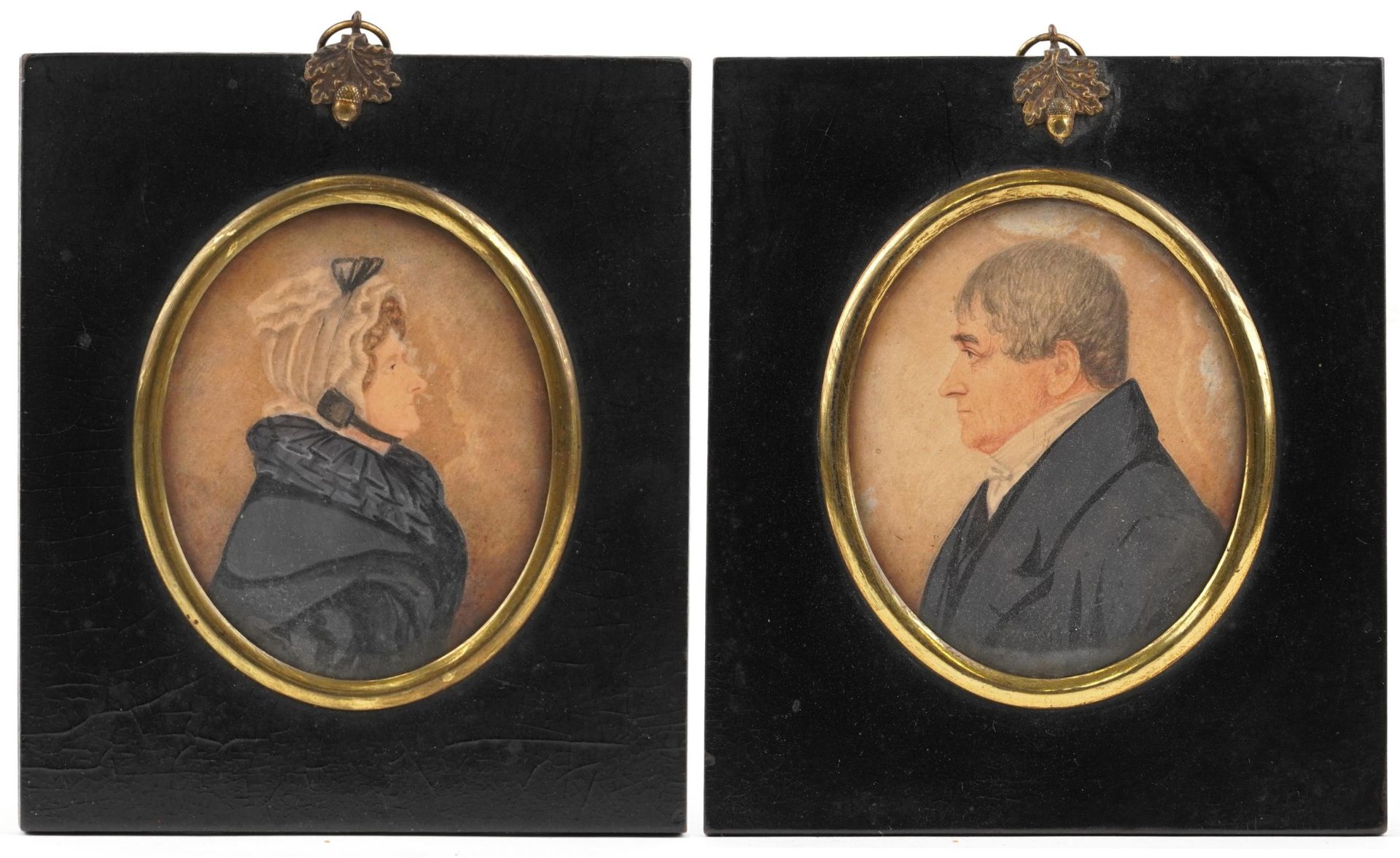 Pair of Georgian oval hand painted portrait miniatures of a male and female housed in ebonised