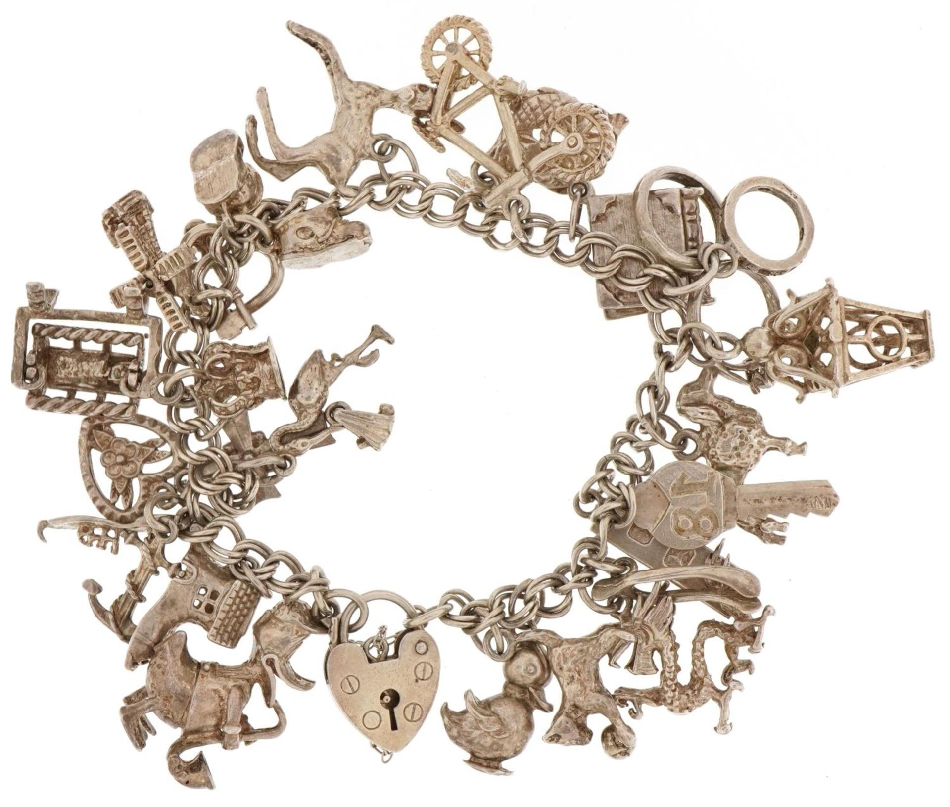 Silver charm bracelet with a large collection of mostly silver charms, 66.6g