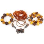 Four Baltic and natural amber necklaces, one with naturalistic white metal setting, total weight