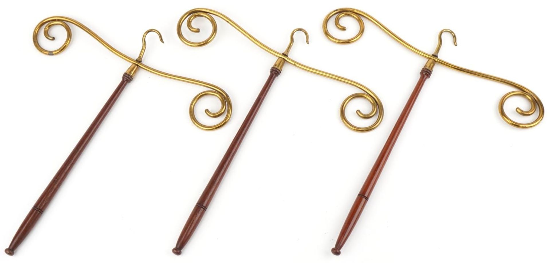 Three Edwardian mahogany and brass gown hangers, each 50cm high