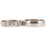 Two Victorian style floral engraved hinged bangles, one in the form of a buckle, each 6.5cm wide,