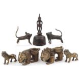 Six African Benin bronzed mythical lions and a figural table bell, the largest 13.5cm high