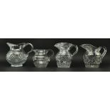 FOUR EARLY 19TH CENTURY GLASS JUGS WITH STEP CUT DESIGN