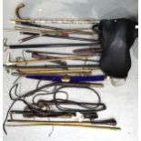 A collection of various walking canes, riding crops, a small saddle marked Barrett (a/f) and other