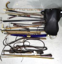 A collection of various walking canes, riding crops, a small saddle marked Barrett (a/f) and other