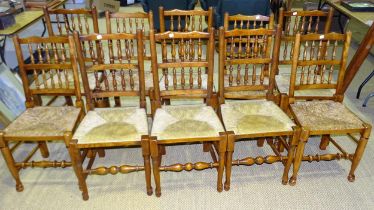 A harlequin set of ten reproduction stained wood country dining chairs with spindle backs and rush