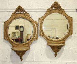 A pair of 19th century gilt gesso-framed wall mirrors, each oval bevelled plate with foliate