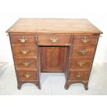 A George III mahogany kneehole desk fitted with nine small drawers, (damaged), around a central