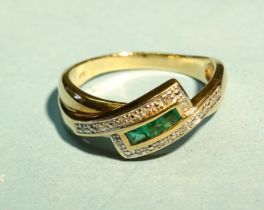 A 9ct gold crossover ring channel-set three square-cut emeralds and twelve 8/8-cut diamond points,