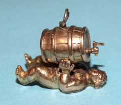A 9ct gold charm of a recumbent figure drinking from a barrel, 10g.