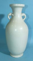 A tall white-glazed Chinese vase with elephant head handles and incised with birds in branches, in