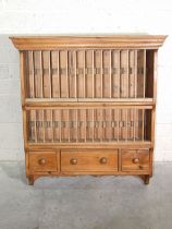 A pine kitchen plate rack with moulded cornice and three small drawers, 89cm wide, 99cm high.