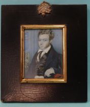 A late-19th century miniature portrait of a young man in a waistcoat with gold chain, on ivory, (