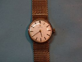 Omega, a lady's 9ct gold wrist watch, the circular silvered face (18mm) with baton numerals, on