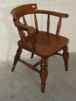 An elm smoker's bow or captain's chair of typical form, on turned splayed legs joined by an H-