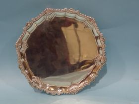 A George V silver salver of shaped circular outline with a shell and scroll border, on scroll