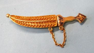 A Middle Eastern yellow metal jambiya brooch with filigree scabbard and safety chain, 5.6cm, 8.8g.