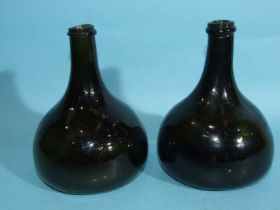 A pair of 18th century green glass onion-shaped wine bottles, (slight chips to one rim).