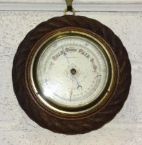 A compensated aneroid barometer/thermometer in circular oak 'rope' frame, 21cm diameter, one other
