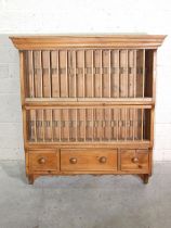 A pine kitchen plate rack with moulded cornice and three small drawers, 89cm wide, 99cm high.