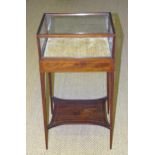 An Edwardian inlaid mahogany display stand, the glazed top on square tapered legs united by an