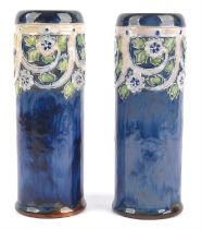 Doulton, a pair of cylinder vases, decorated with raised flowers and leaves, amidst strapwork,