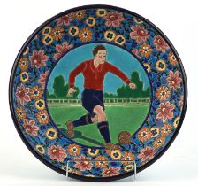 Longwy, a pottery charger decorated with a football player, printed marks to base, 38.5cm diameter
