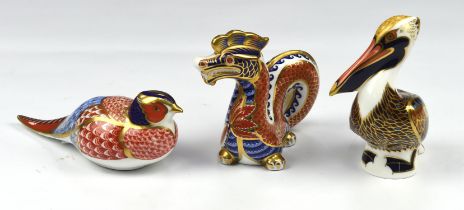 Three Royal Crown Derby porcelain paperweights, to include a peacock, with gold stopper, a dragon,