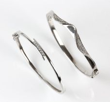 Two cubic zirconia set hinged bangles, one with wavy design, in silver, 59mm inside diameter,