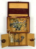 A red leather jewellery box containing costume jewellery, including two silver amber pendants,