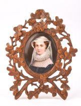 A South German limewood carved frame with miniature, early 20th century, the central oval with a