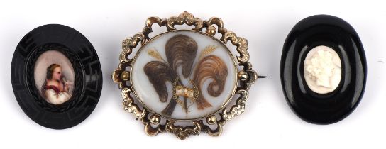 A mourning brooch with a central hair compartment in tested 9 ct, and two jet brooches,