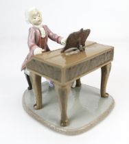 A Lladro porcelain figure of Mozart at his piano, in a lilac frock coat, underside bearing Lladro