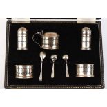 Cased 8 piece pierced silver cruet set with blue glass liners.