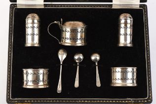 Cased 8 piece pierced silver cruet set with blue glass liners.