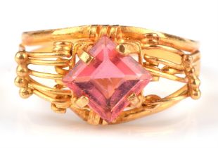 An Egyptian ring, with central pink paste stone, in an openwork mount bearing Egyptian marks for 21