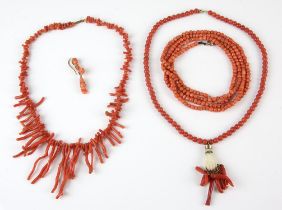 Three coral necklaces including hand pendant holding items carved from coral