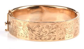 Gold hinged bangle in 9 ct, with carved foliate designs to the surface of the bangle,