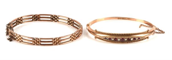 Two gold bangles, including a gate style hinged bangle and a garnet and pearl hinged bangle,