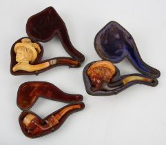 Three meerschaum pipes, 19th Century, two carved with heads of ladies in feathered hats,