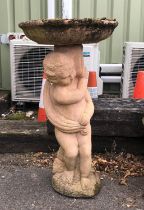 Reconstituted stone bird bath supported by a naked cherub, H74cm