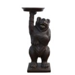 A Black Forest style carved and painted bear occasional table, the standing bear holding up a