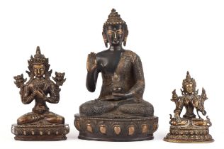 Three Himalayan, or other Asian, metal deities comprising: one figure seated in dhyanasana on a