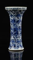 A small blue and white trumpet vase, decorated with typical panels of floral or natural history